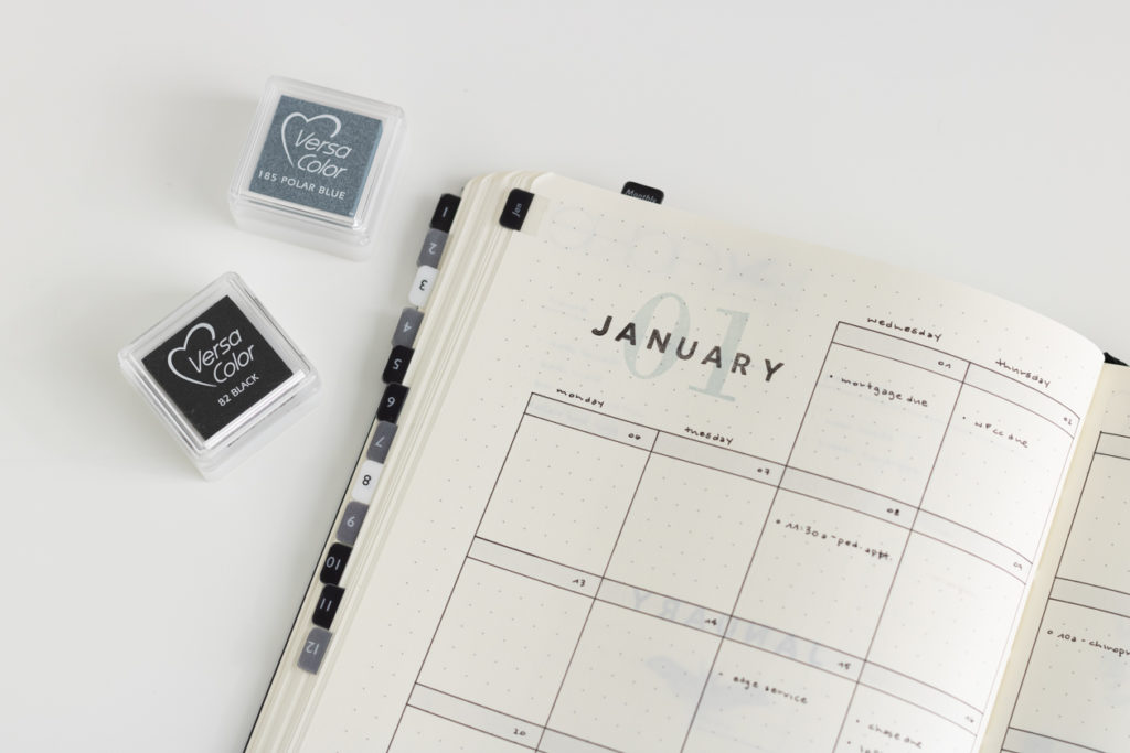 a detailed view of a january monthly bullet journal spread by plan another day with two ink pads next to the notebook